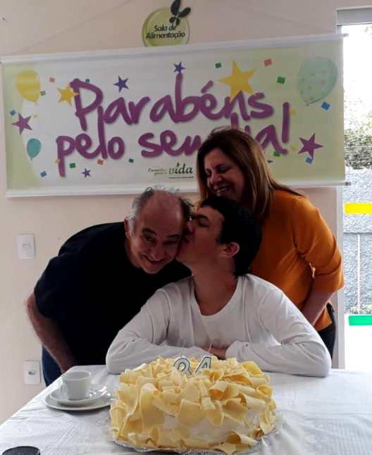 Foto de um dos nossos atendidos, João, comemorando seu aniversáro de 34 anos de idade junto aos seus pais, Raquel e David.