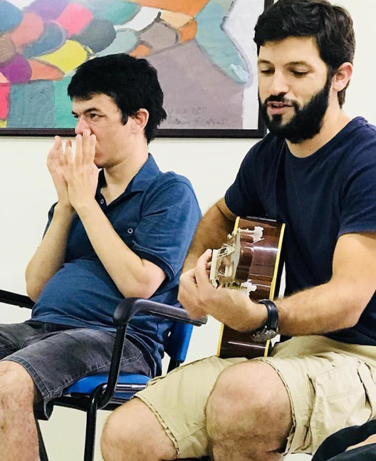 Foto de um dos nossos atendidos, João, junto ao profissional Rui, praticando atividade de som e movimento.